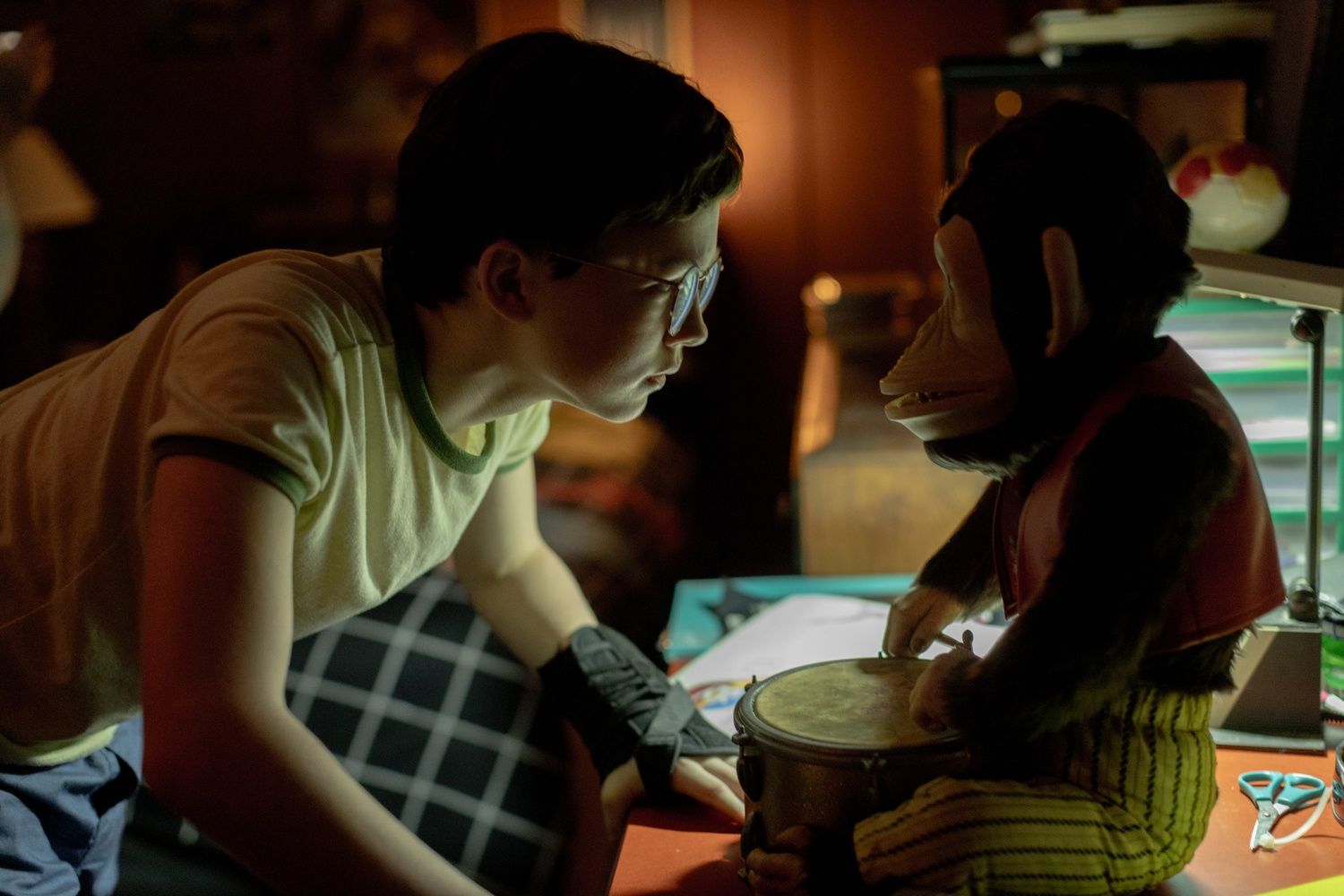 A young boy observes a toy monkey with trepidation