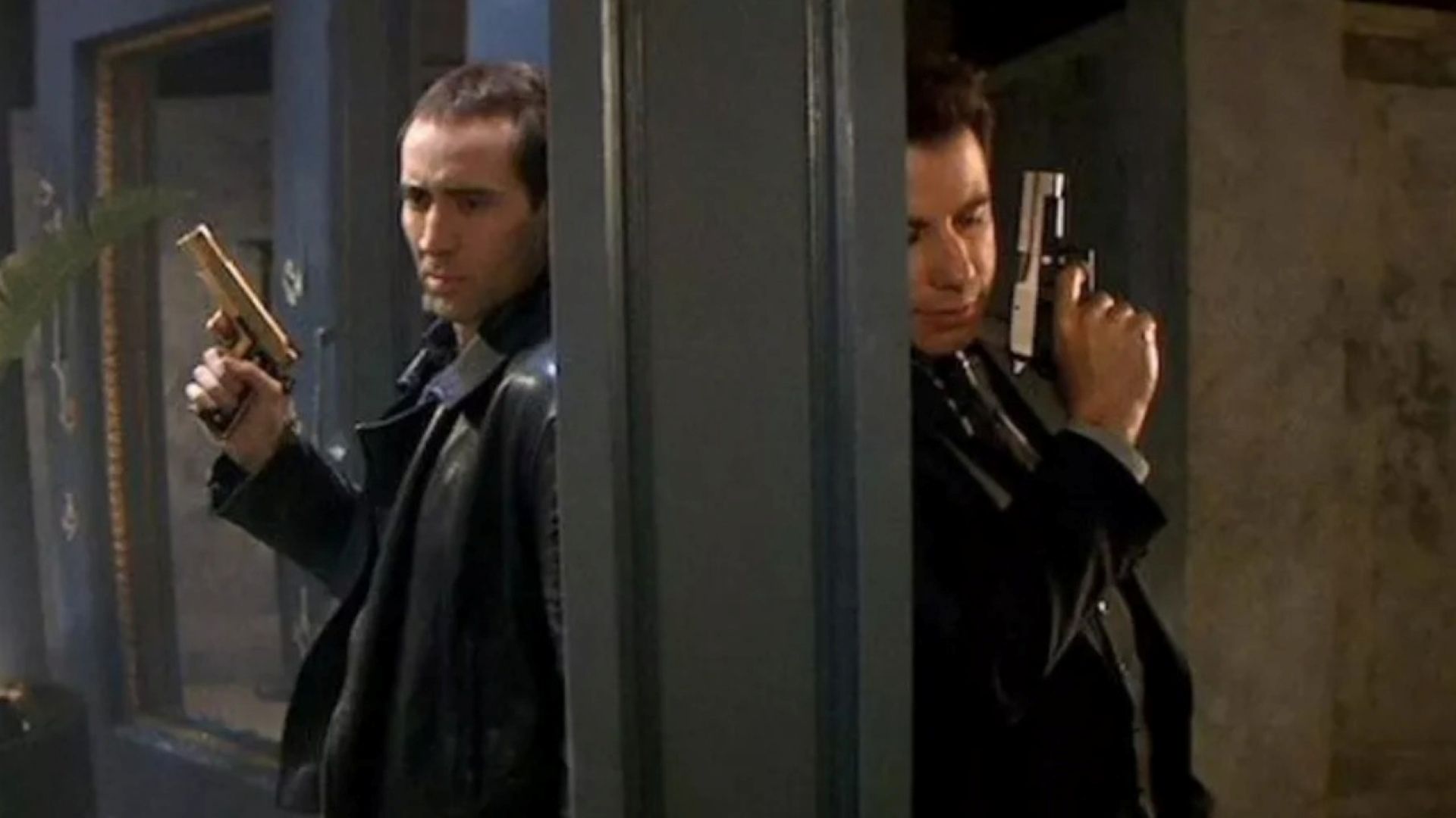 Nicolas Cage and John Travolta stand back-to-back, separated by a two-sided mirror, in a scene from Face/Off