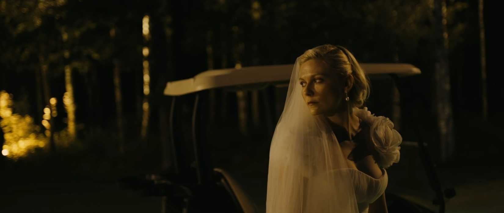 कर्स्टन डंस्ट फिल्म मेलानचोलिया से शाम के सेट के दृश्य में शादी की पोशाक में गहराई से दुखी दिखते हैं