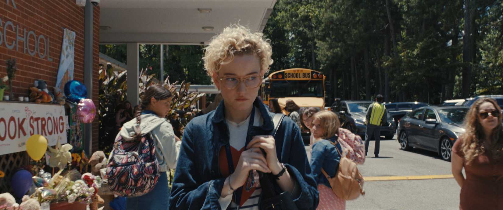 Justine (Julia Garner), a third-grade teacher, walks away from her school in a crowd of kids, looking upset, in 2025's Weapons