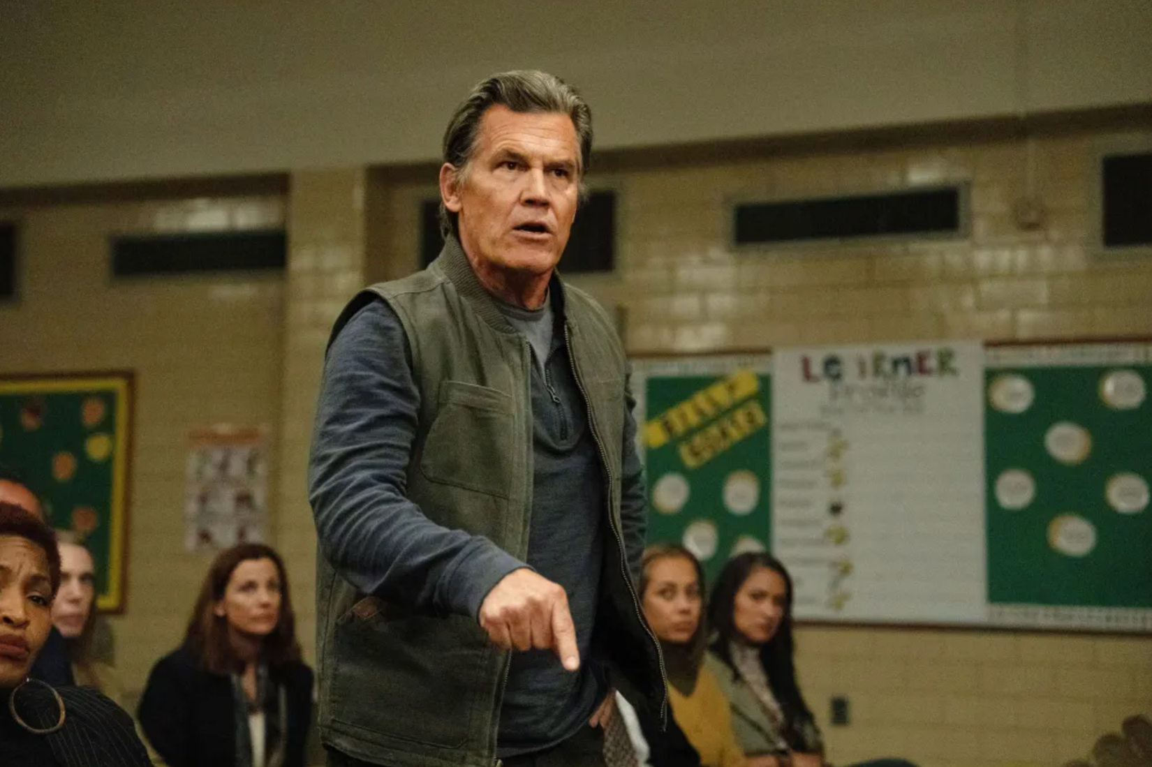 Josh Brolin stands up during a meeting at a school in Weapons