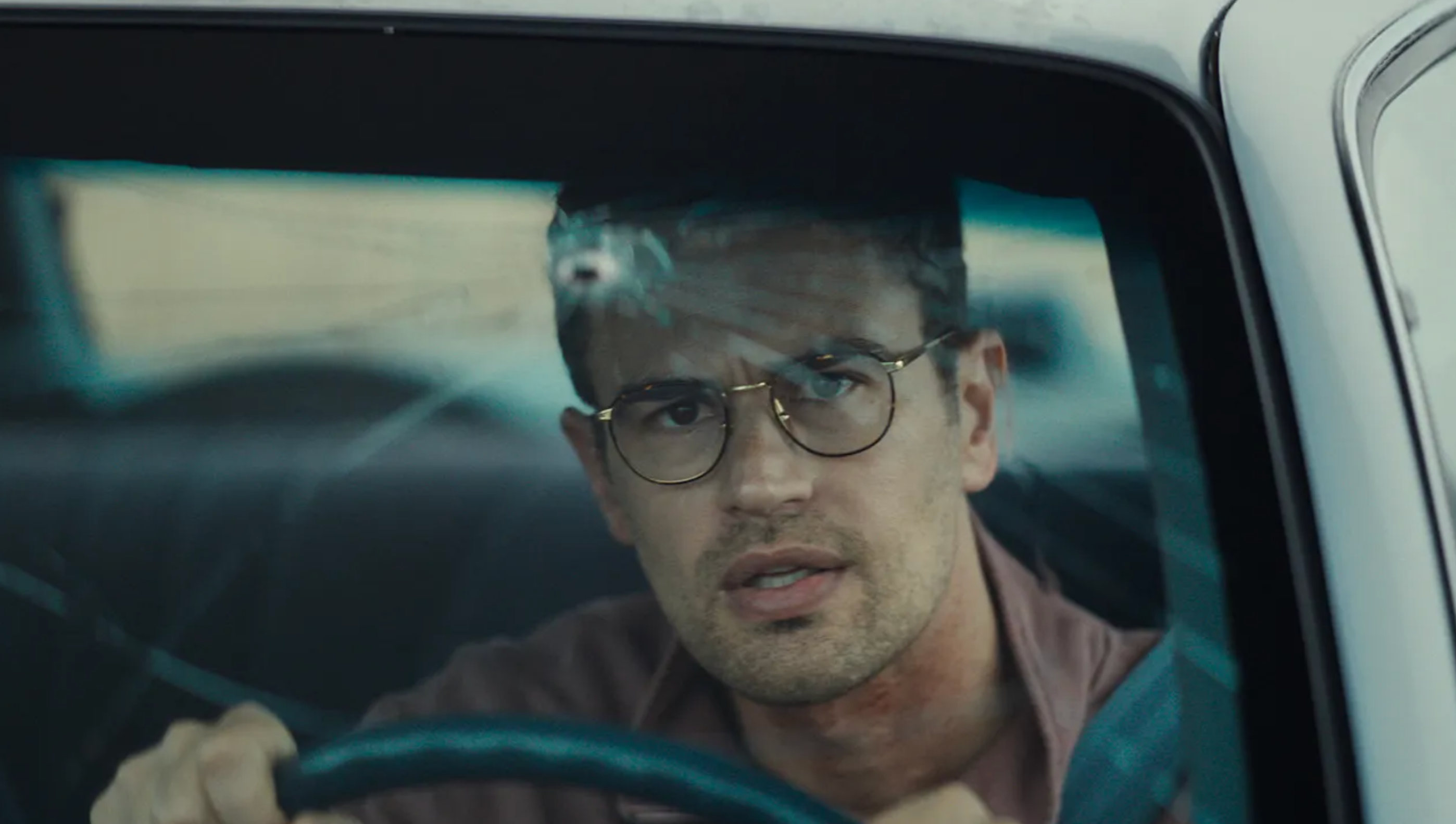 Theo James stares through a cracked car windshield in The Monkey