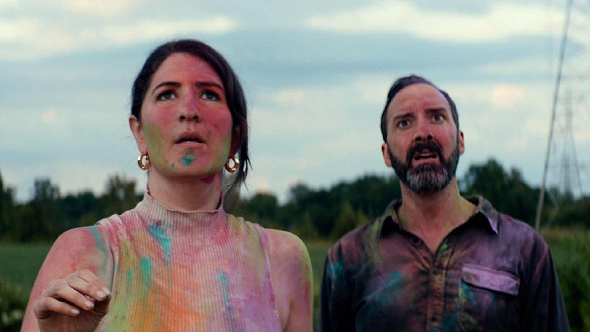 Tony Hale and D'Arcy Carden are covered in eerie colorful ink as they counter an offscreen monster created from a child's drawing in a scene from Sketch.