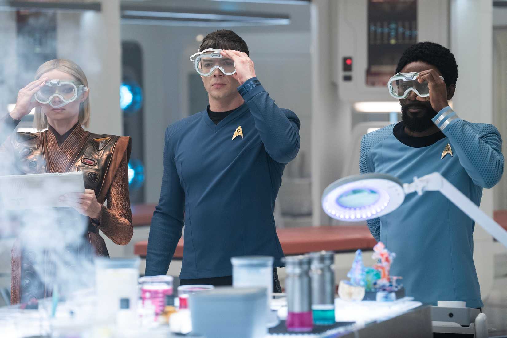 Jess Bush as Chapel, Ethan Peck as Spock and Babs Olusanmokun as Dr. M'Benga perform a science experiment in Star Trek: Strange New Worlds