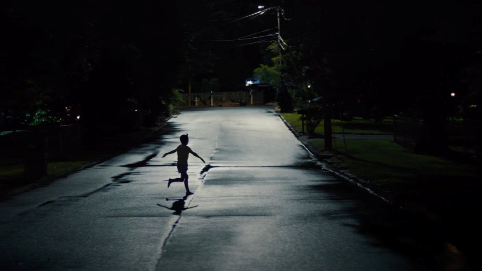 A shadowy image of a child running with his arms out into the street in the dead of night in a scene from Weapons. 