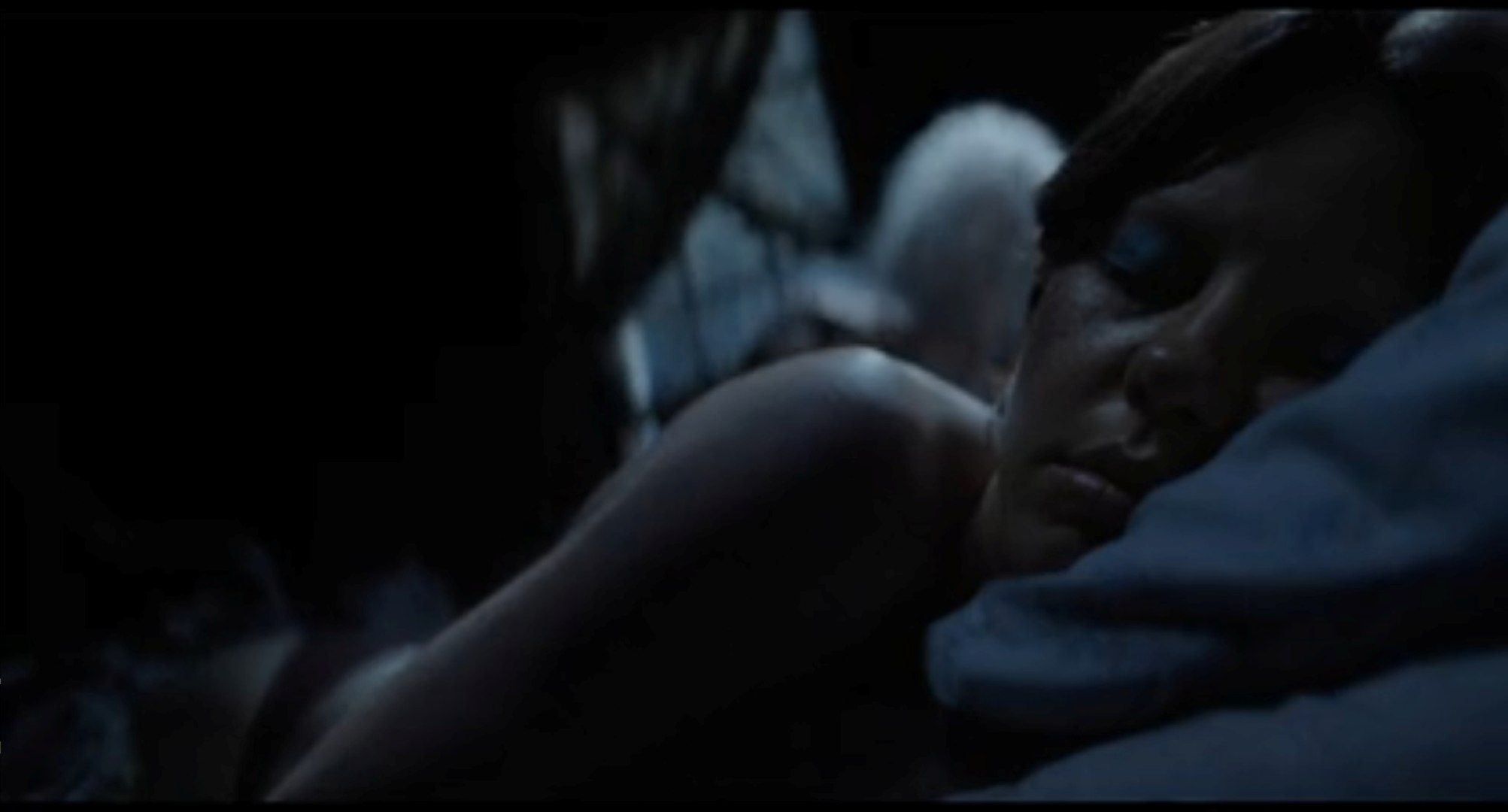 In a scene from the horror movie X, a ghostly figure in the background climbs into bed with Maxine, a young woman sleeping in the foreground